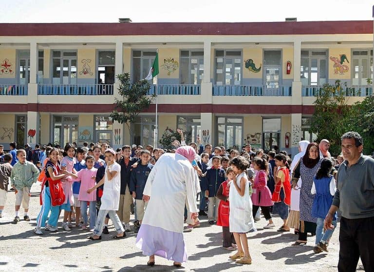 Schoolchildren and teachers gathered in a primary school courtyard in Algeria.