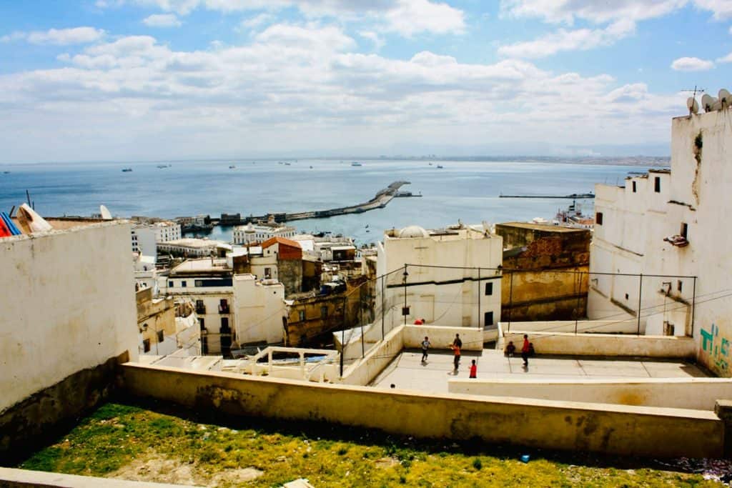 Basketball court among the white buildings of the Casbah of Algiers overlooking the sea.